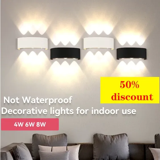 Four CANMEIJIA curved wall lamps in black and white on a living room wall, each throwing warm up-and-down beams above a sofa