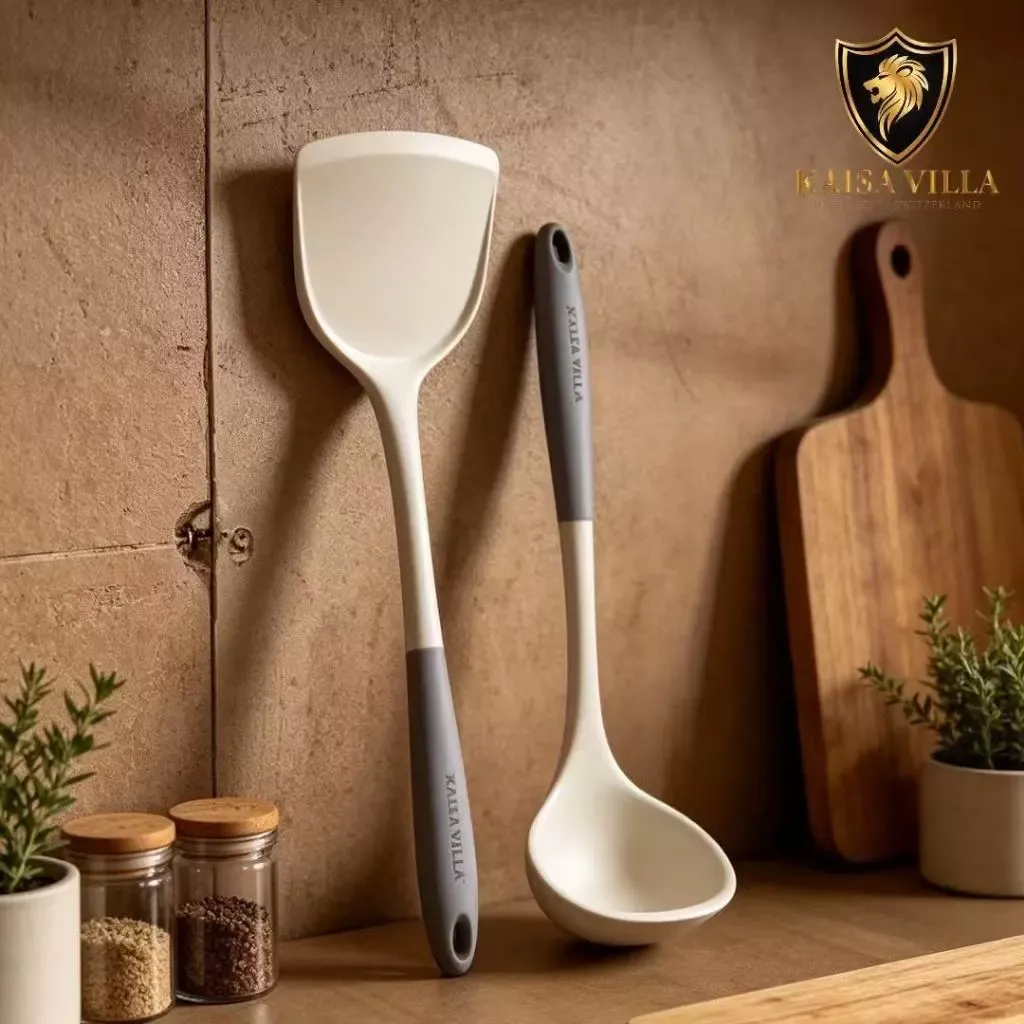 Kaisa Villa two-piece cream silicone set, a wide turner and a deep ladle with grey handles, leaning on a wall