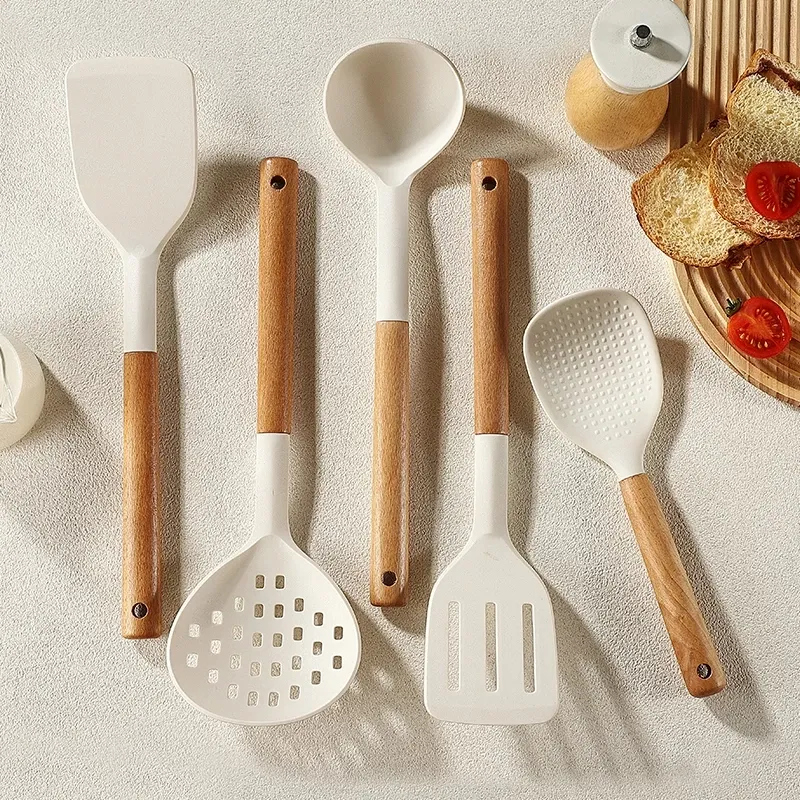 LOCAUPIN five-piece white silicone kitchen tool set with wooden handles laid flat on a pale surface